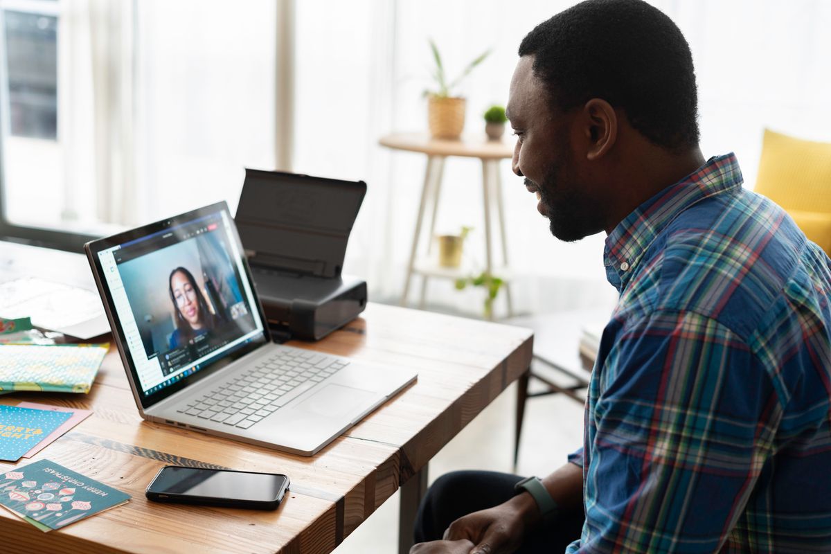 A consultant smiling on a video call with a client on his laptop